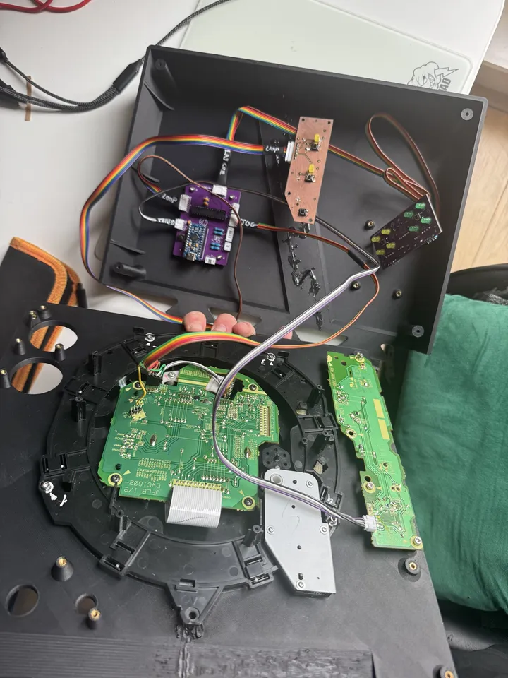 An open printed base holding the purple controller board and a copper-coloured home-made board with LEDs and switches, joined by rainbow ribbon cable to the top plate, where the CDJ's jog and side boards are mounted.