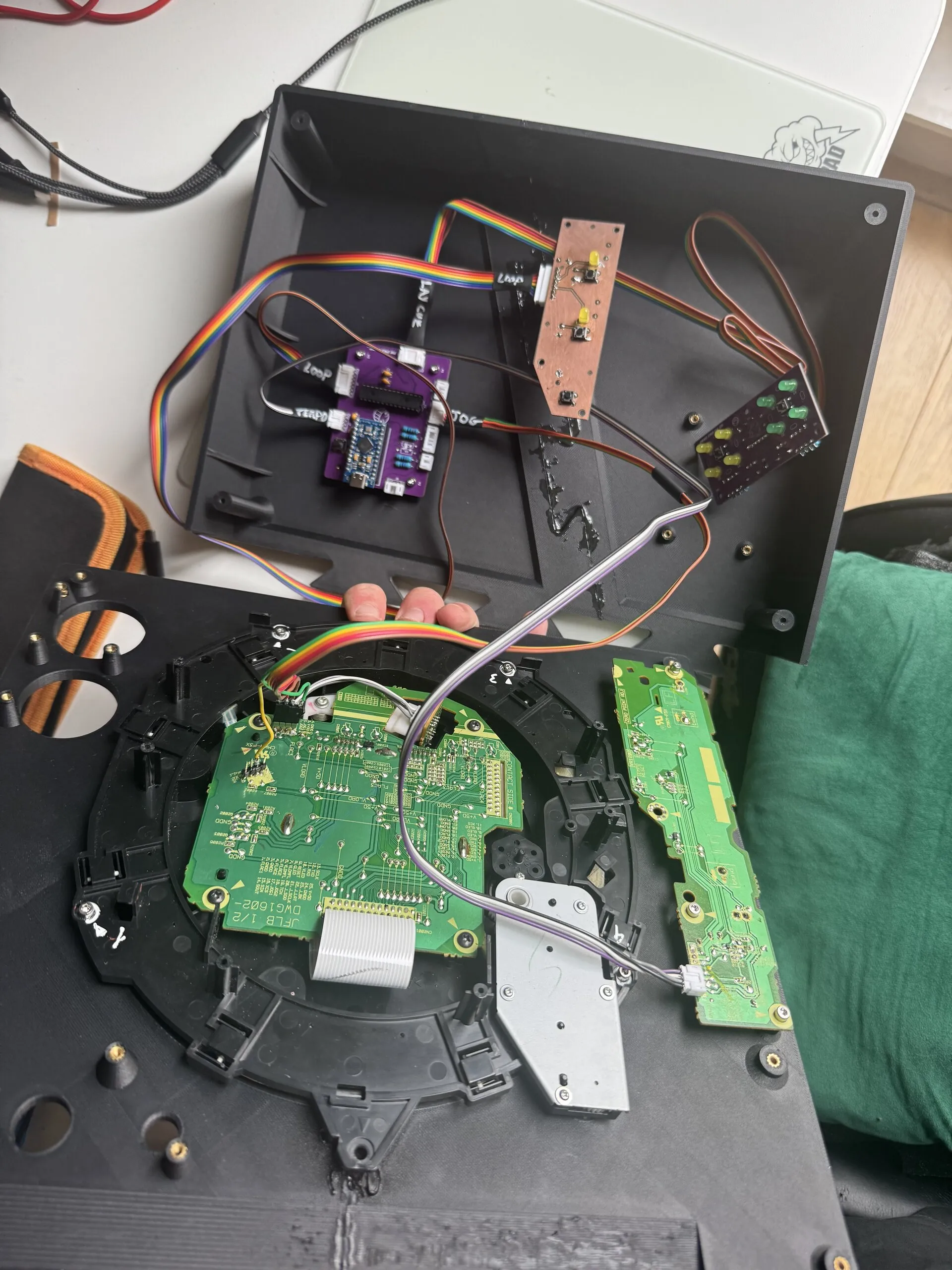 An open printed base holding the purple controller board and a copper-coloured home-made board with LEDs and switches, joined by rainbow ribbon cable to the top plate, where the CDJ's jog and side boards are mounted.
